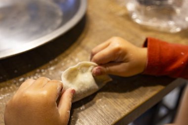  Bir çift hassas küçük el dikkatlice hamur köftelerini paketliyor.