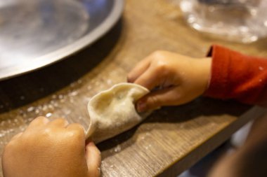  Bir çift hassas küçük el dikkatlice hamur köftelerini paketliyor.