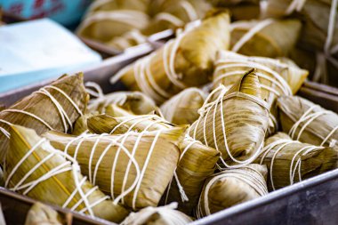 Bir kap bambu yapraklarına sarılmış ve iple bağlanmış geleneksel zongzi ile doludur.