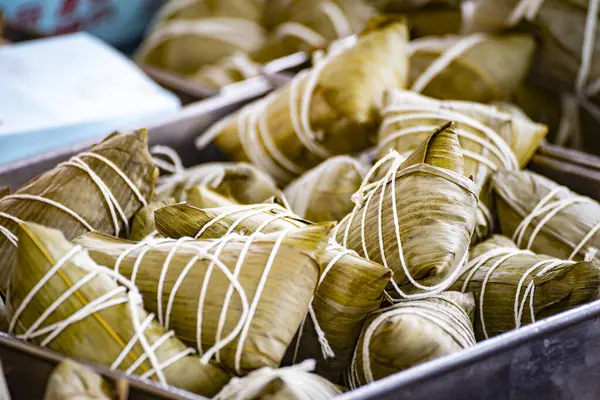 Bir kap bambu yapraklarına sarılmış ve iple bağlanmış geleneksel zongzi ile doludur.