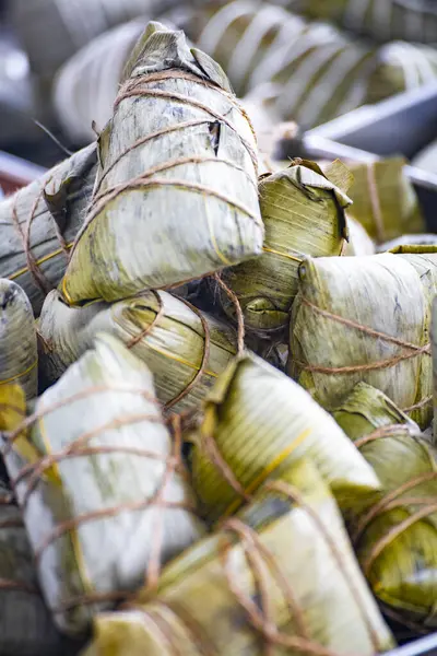 Bir kap bambu yapraklarına sarılmış ve iple bağlanmış geleneksel zongzi ile doludur.