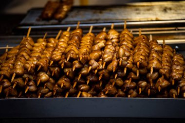 a large pile of grilled chicken butt skewers neatly arranged on a grill
