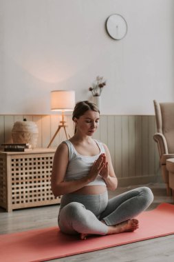 Genç hamile anne yoga yapıyor. Evde spor giyim bölümünde hamile bir kadın var. Yüksek kalite 4k görüntü