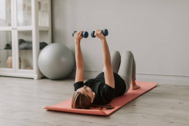 Spor giyimli, mutlu ve hamile bir kadın oturma odasında egzersiz yapıyor. Hamilelik süresince yaşam tarzını, sağlık hizmetlerini ve sporu kavramsallaştır. 4 bin. Yüksek kalite 4k görüntü