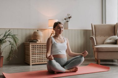 Genç hamile anne yoga yapıyor. Evde spor giyim bölümünde hamile bir kadın var. Yüksek kalite 4k görüntü