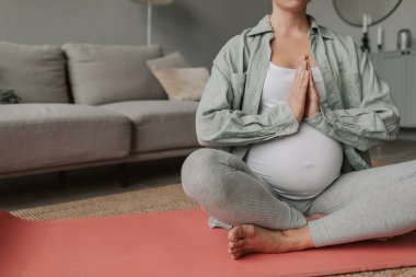 Hamile bir kadının vücudu rahat bir iç çamaşırı giyer, meditasyon yapar lotus pozisyonunda oturur ve nefes alma egzersizleri yapar. Yoga, hamilelik sırasında refahı koru. Yüksek kalite