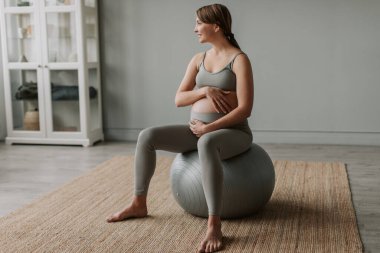 Spor giyim sektöründe hamile bir kadın evde spor salonunda meditasyon yapıyor. Doğum öncesi solunum jimnastiği. Koca göbekli ve doğmamış bir bebeği var. Sağlıklı imaj kavramı. Hamile kadınlar için spor
