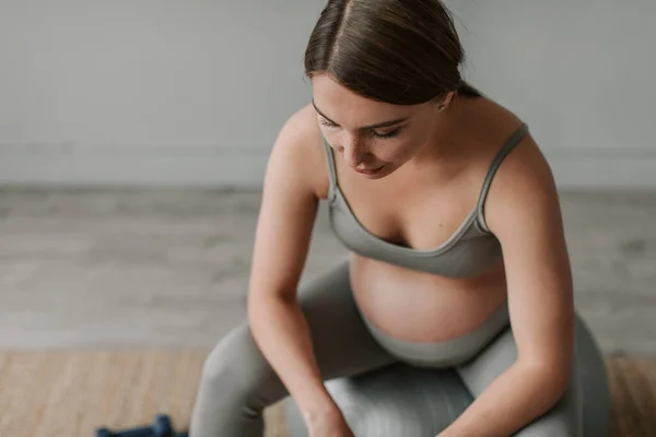 Close up shot of attractive tired pregnant female wipe the sweat from forehead by hand, having rest sitting in living room at home. Healthy Pregnancy concept 4K. High quality 4k footage