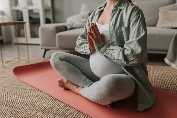 Pregnant woman wear light wear sit cross-legged meditating breathing exercises, body part close up. Training to decrease lower back pain, reduce fears before childbirth, pregnancy yoga concept.