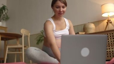 Hamile kadın, oturma odasında koca göbekli bir şekilde internette yoga yapıyor. Yüksek kalite 4k görüntü