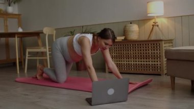 Genç bayan evde geriniyor. Genç bayan oturma odasında hamileliği sırasında egzersiz minderinde yoga yapıyor. Sağlıklı bekar anne online derste çalışıyor. Esneme, hamilelik yoga konsepti 4k