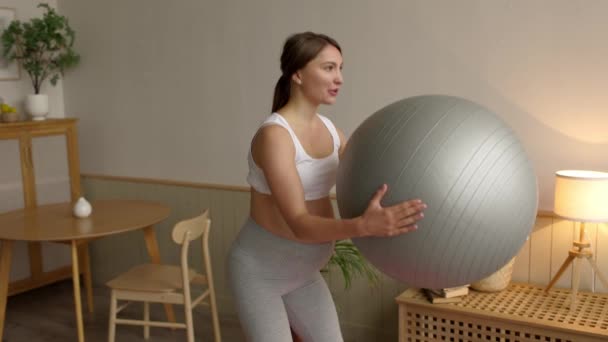 自宅でフィットネスボール室で運動をする魅力的な妊婦 フィットボールで身をかがめる柔軟な美しい女性をスポーツ 幸せな健康的な妊娠の概念4K 高品質4K映像 — ストック動画