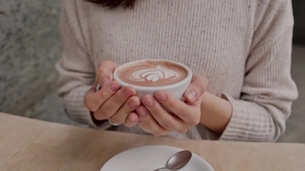 喝了一杯热拿铁艺术咖啡的心满意足的女人在早上坐在桌旁喝了一杯热咖啡 迷人的女士慢动作地享受着一杯咖啡 高质量的 — 图库视频影像