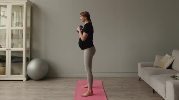 Yatay Genç Hamile Bir Kadın Oturma Odasında Dambıllarıyla Egzersiz Yapıyor — Stok video