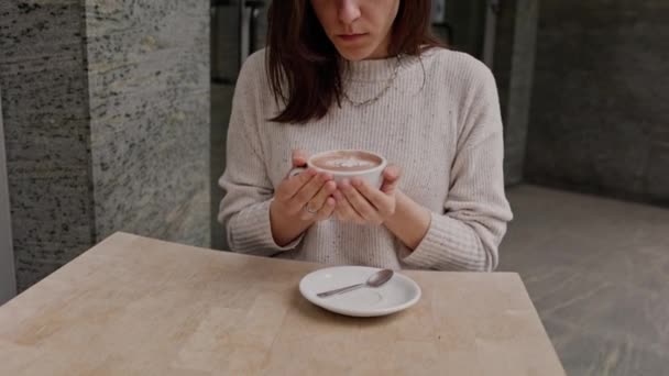 女性の手はコーヒーを一杯飲む 女性は熱いコーヒーカップで手を暖める ズームアウトショット 高品質4K映像 — ストック動画
