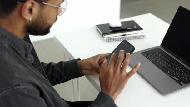 Černoch Muž Sedí Bílého Stolu Před Notebookem Drží Mobilní Telefon — Stock video