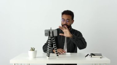 Neşeli, yakışıklı Afrikalı bir adam, gözlüklü bir etkilidir. Telefon kamerasını tripoda yerleştirip, sosyal ağlardaki takipçilere yeni kulaklık ya da cihaz sunumu hakkında video yayınlar.