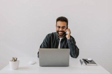 Gülümseyen yetişkin, karışık ırk profesyonel iş adamı iş görüşmesi yapıyor ev telefonuyla konuşuyor, mutlu Afro-Amerikan satış elemanı kapalı alanda mobil sohbetten hoşlanıyor. 