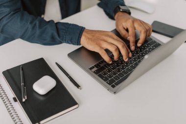 Orta ölçekli bir Afrikalı Amerikalı 'nın laptopta yazı yazıp mesaj yazarken, beyaz havai ofisteki masada otururken, kapalı alanda siyahi yetişkin öğrenci çalışması yaparken, kripto meraklısının hisse senetlerini ararken görüntüsü. 