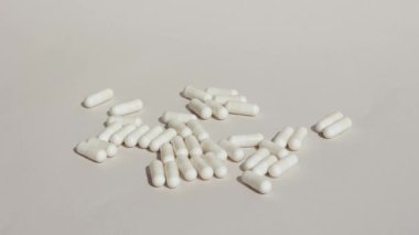 White pill capsules drop on white background with pills . Medicine capsules. The concept of healthcare and pharmaceutical production. Feeling unwell, hospital. High quality 4k footage