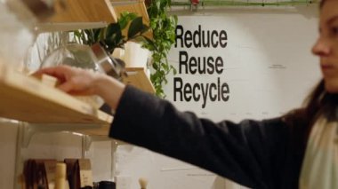 Genç kadın, yeniden kullanılabilir cam kavanoz, sıfır atık market ve plastiksiz, çevre dostu, sürdürülebilir yaşam tarzlarından organik ürünler seçip alıyor. Yüksek kalite 4k