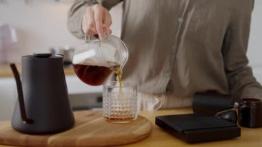 Genç bir bayan taze damlayan kahveyi evdeki mutfaktaki bardağa dolduruyor. V60 metodlu ev yapımı kahve seti. Yüksek kalite 4k görüntü