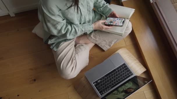 トップビュー女性は 自宅の窓の近くの木の床に座ってラップトップを使用してオンラインで勉強しています 高品質の4K映像 — ストック動画