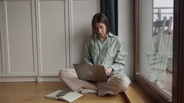 迷人的年轻女人 穿着睡衣 在家里的客厅里 盘腿坐在靠近窗户的地板上打字 高质量的4K镜头 — 图库视频影像