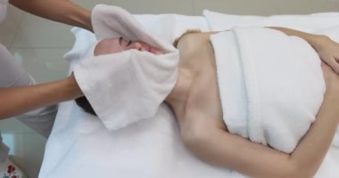 Usta bir güzellik uzmanı müşterileri havluya sarar. Yakın plan. Kozmetik Kliniği. Yüksek kalite 4k görüntü