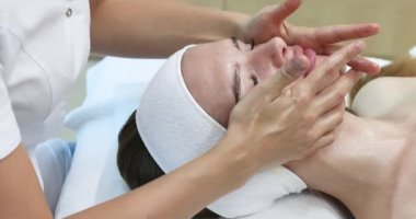 Kaplıca salonunda yüz masajı yapan çok güzel bir kız. Sağlıklı bir yaşam tarzı. Yüksek kalite 4k görüntü