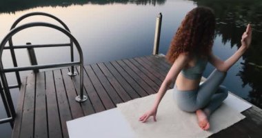 Yoga yapan güzel kız. Jetty göl kenarında. Sabahları yoga. Pilates. Rahat ol. Asana. Yüksek kalite 4k görüntü