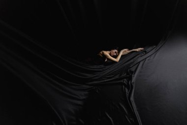  Balerin siyah saten kumaşın üzerinde yatıyor. Yüksek kalite fotoğraf