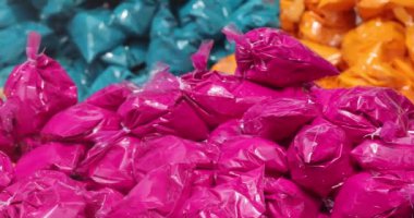 Colured powder in plastic market pack organic, herbal Holi gulaal colors in plastic polythene packs to be sold by weight on street color kept in bag for sale, selective focus festival of colors. High