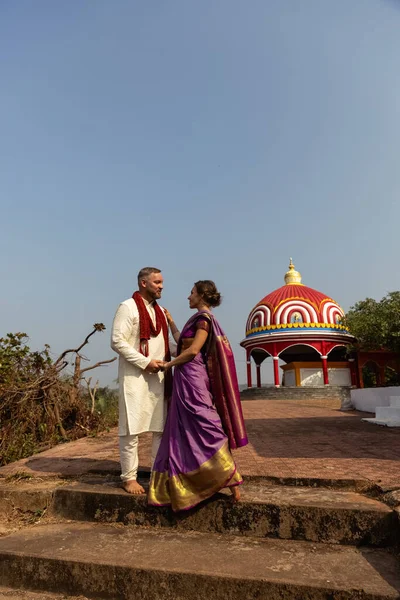 Wedding of a couple from Europe in India. A light skinned man in a traditional Indian men. white skin. Bride in beautiful sari with mehendi. Caucasian marriage . High quality photo