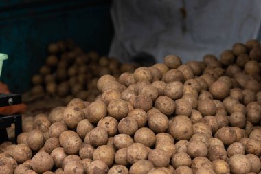 Yerel çiftçi pazarında bir sürü patates birikiyor. Ateş gün ışığında edildi. Marketin sebze bölümünü gösteriyor. Yüksek kalite fotoğraf