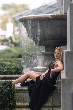 Şehirde akan bir çeşmenin önünde güzel bir Kafkas sarışını. İnce ve çekici, yakınında bir kuş tünemiş ve model tarzı makyaj yapıyor. Yüksek kalite fotoğraf