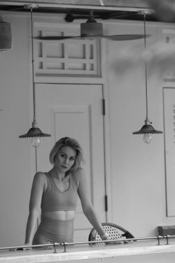 Açık renk saçlı güzel, ince bir kız yoga ya da pilates yapıyor. O, turuncu bir spor giysi giydi. Tozlu güzel bir atletik kız. Spor ve spor anlayışı..