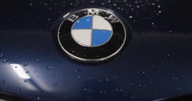 Berlin, Almanya... 10.04.2022 BMW logosu yeni bir arabanın kaputunda. Servis az önce arabayı yıkadı. Logonun etrafında su damlacıkları var. Yüksek kalite 4k görüntü