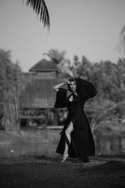 Güzel beyaz bir sarışın siyah bir şapka takarak doğada yürüyor. Pahalı bir otelin arazisinin lüksü. Yüksek kalite fotoğraf