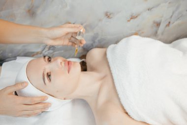  Güzellik uzmanının, bir kadının yüzüne pipetli cilt bakımı ve kozmetik yağıyla yağ sürme sürecinin yakın çekimi. Profesyonel tedavi serumu yağı. Yüksek kalite fotoğraf