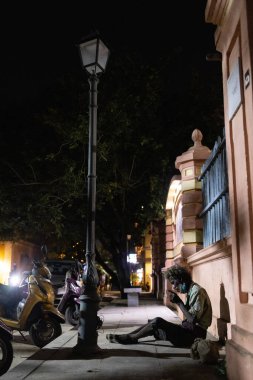 PUDUCHERRY, Hindistan - 7 Şubat 2023: Sabit ikametgahı olmayan bir kişi şehirde sokakta oturuyor. Yüksek kalite fotoğraf