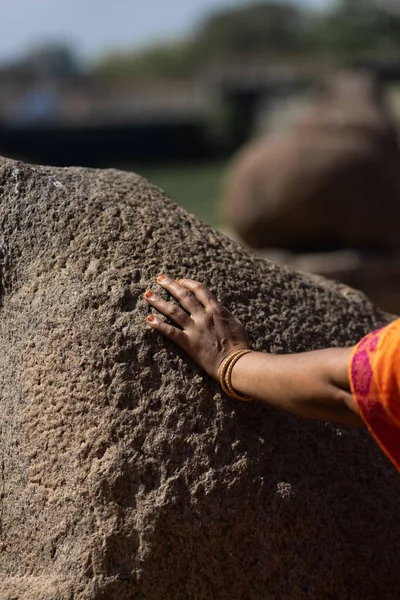 The woman touches a stone with her hand on a sunny day. Close-up of the hand. The concept of human and nature. High quality photo