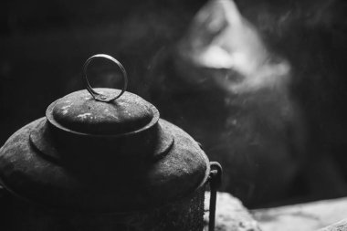 Kapağı ateşten kararmış bir tencere. Ateşin üstünde yemek hazırlamak için yemek takımı. Yemek takımının siyah rengi kuruma bağlıdır. Yüksek kalite fotoğraf