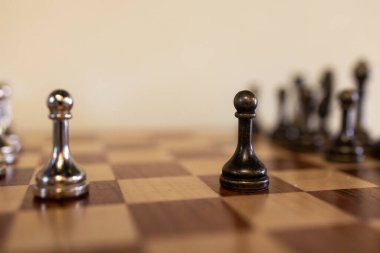 Bir kişi tarafından hareket ettirilen satranç taşı ön planda görünür. Kapalı alanda bir satranç oyunu sırasında ışıkta. Yüksek kalite 4k görüntü