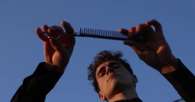  Yakışıklı Berber elinde bir tarak ve makas tutuyordu. Kuaför. Saç kesmeyi öğrenmek için. Kuaför. Yüksek kalite 4k görüntü