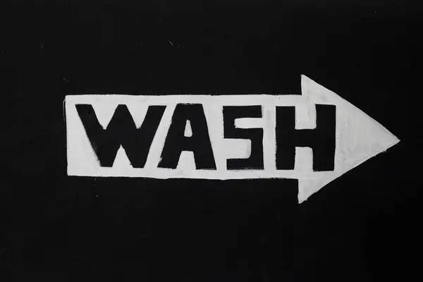 A sign with the word wash in white font on a black background.Car wash. Sign.Car wash. Sign.A white drawn arrow on a black background. High quality photo