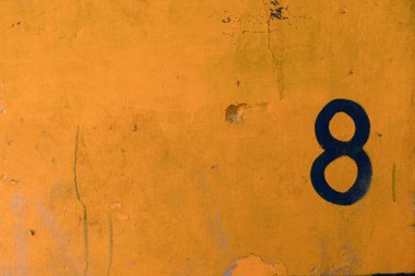 The number 8, painted in black on the yellow wall of a house, creates a strong contrast. High quality photo clipart