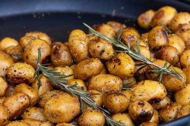 Biberiye ve tuzla süslenmiş zeytinyağı serpiştirilmiş, aromatik otlar ve baharatlarla tatlandırılmış yakın plan patates. Yemek konsepti. Yüksek kalite fotoğraf