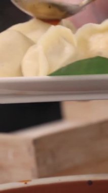 Bir şef geleneksel Çin böreklerinin üzerine yemek tezgahı ya da yiyecek pazarında sos döker. Yüksek kalite 4k görüntü