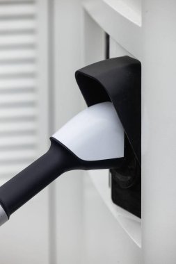 Kapalı EV şarj kolu fişe takıldı veya elektrikli arabaya bağlandı, EV araba aküsünü temiz çevre için sıfır CO2 emisyonu ile alternatif ve sürdürülebilir enerjiyle şarj etti. Yüksek kalite fotoğraf
